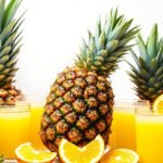 Fresh pineapple surrounded by glasses of pineapple juice